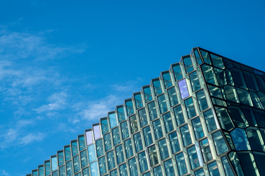 Glass office building facade against a blue sky